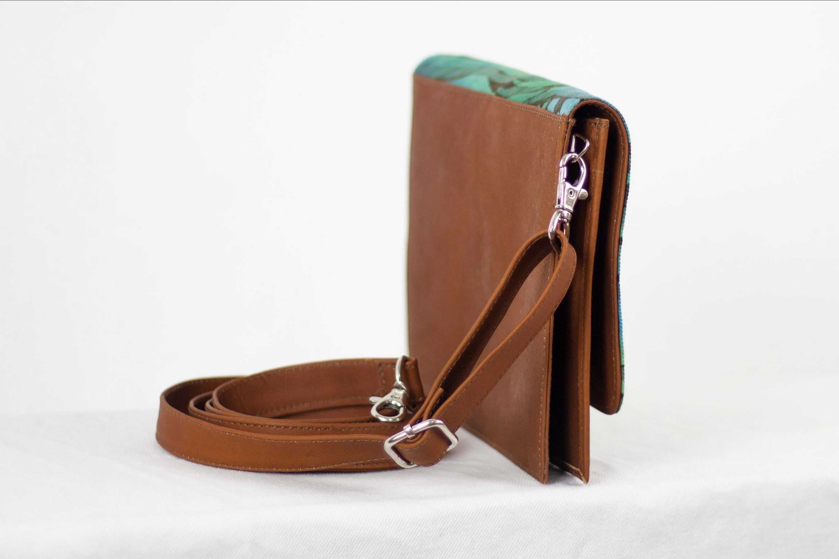 Rear view of Hand painted, leather trimmed cross body tote with the green and blue “Boo Verdi Blue” pattern. It has a solid leather back