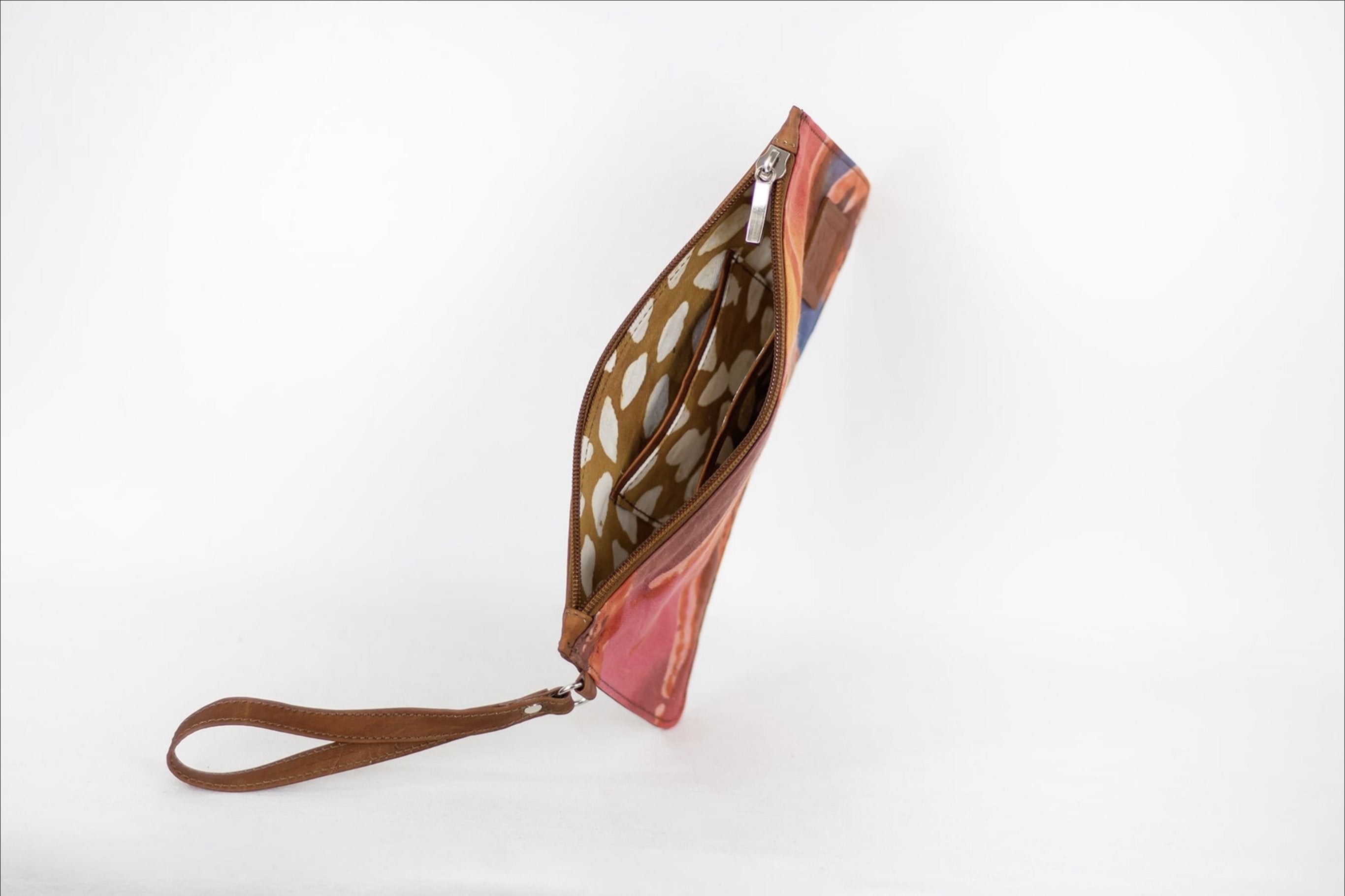Hand painted, leather trimmed clutch purse with the red, orange and blue “fire palm” pattern. It has white polka dot lining.